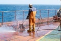 crew member of a cargo ship derusting on deck for surface preparation before painting using high pressure hydroblust gun Royalty Free Stock Photo