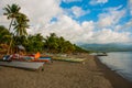 Sea, palm trees, mountains and local boats on the volcanic beach. Pandan, Panay island, Philippines. Royalty Free Stock Photo