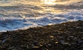 Sea pebble beach with multicoloured stones, waves with foam Royalty Free Stock Photo