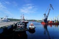 Sea port crane and tugboats towed to the pier. Royalty Free Stock Photo