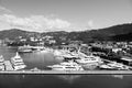 Sea port and town on sunny blue sky. Yachts moored at sea pier on mountain landscape. Luxury travel on boat, water