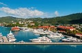 Sea port and town on sunny blue sky. Yachts moored at sea pier on mountain landscape. Luxury travel on boat, water