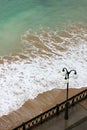 sea promenade with lantern and sand beach in stormy weather with waves Royalty Free Stock Photo