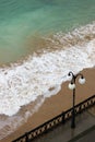 sea promenade with lantern and sand beach in stormy weather with waves Royalty Free Stock Photo