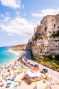 Sea promenade scenery in Tropea with high cliffs with built on top city buildings and apartments. Rotonda beach full of people.