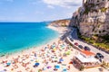 Sea promenade scenery in Tropea with high cliffs with built on top city buildings and apartments. Rotonda beach full of people.