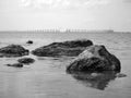 Sea, rocks, bridge in the background. Black and white photography emphasizes the contrast between stone and water. Royalty Free Stock Photo