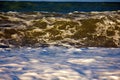 Sea rolling and receding water in rays of setting sun. Royalty Free Stock Photo