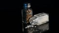 Sea Salt and Black Pepper displayed in glass Jars on black backgound