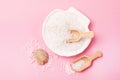 Sea Salt Crystals in White Bowl in Shape of Shell Small Wooden Scoop with Sea Salt and Shell Pink Background Copy Space