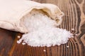 Sea salt in jute sack on wooden table.