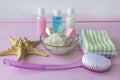 Sea salt with minerals for body spa care. Massage brush and cosmetic skin cleansers on pink background. Spa concept, relaxation