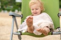 Sea sand on the feet of a child. A little girl covered with a towel sits on a folding chair, her feet are wet in the sand Royalty Free Stock Photo