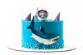 Sea and shark themed cake with blue cream cheese frosting on the white background. Diver in a mask. Snorkelling among the sharks.