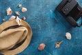 Sea shells, beach hat and photo camera on blue wooden background Royalty Free Stock Photo