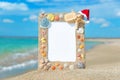 Sea shells frame with christmas hat against sea beach