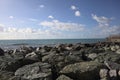 Sea with a ship on the horizon on a sunny day framed by boulders of the breakwater