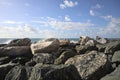 Sea with a ship on the horizon on a sunny day framed by boulders of the breakwater