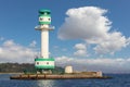 A green and white lighthouse in the Kiel Fjord in sunshine.