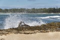 Sea spray flys through the air as waves crash over driftwood