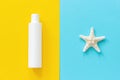 Sea starfish and white bottle of sunscreen on yellow and blue paper background. Mock up Template for lettering, text or your