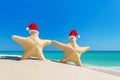 Sea stars couple in red Santa hats at sandy tropical beach Royalty Free Stock Photo