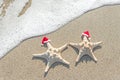 Sea-stars couple in santa hats on the sand. Royalty Free Stock Photo