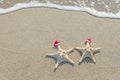 Sea-stars couple in santa hats on the sand. Royalty Free Stock Photo