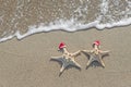 Sea-stars couple in santa hats on the sand. Royalty Free Stock Photo