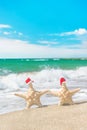 Sea-stars couple in santa hats walking at sea beach Royalty Free Stock Photo