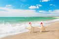 Sea-stars couple in santa hats walking at sea beach. Royalty Free Stock Photo
