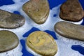 Sea stones in white foam, water-drenched fragments of stones of natural origin, on a blue background. Stones are used for Massage