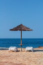 Sea with sun umbrella, white deckchair on flagged stone beach. Vactaion, travel background, Croatia, Istria