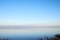 Sea at sunset with clear blue sky making a nature mirror reflection on the water with golden grey clouds on the horizon Royalty Free Stock Photo