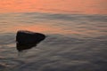 Sea sunset, a large stone in the water in the foreground and against the backdrop of the orange sea and the setting sun Royalty Free Stock Photo