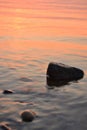 Sea sunset, a large stone in the water in the foreground and against the backdrop of the orange sea and the setting sun Royalty Free Stock Photo