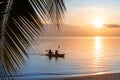 Sea sunset, ocean sunrise, tropical island beach, palm tree leaves, blue water wave, two people silhouette in boat, kayak, canoe Royalty Free Stock Photo