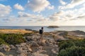Sea sunset view. Man with backpack on rocks with beautiful view of Yeronisos Island near coast of Agios Georgios Pegeias Royalty Free Stock Photo