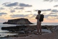 Sea sunset view. Man with backpack on rocks with beautiful view of Yeronisos Island near coast of Agios Georgios Pegeias Royalty Free Stock Photo