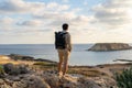 Sea sunset view. Man with backpack on rocks with beautiful view of Yeronisos Island near coast of Agios Georgios Pegeias Royalty Free Stock Photo