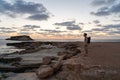 Sea sunset view. Man with backpack on rocks with beautiful view of Yeronisos Island near coast of Agios Georgios Pegeias Royalty Free Stock Photo