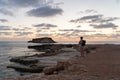 Sea sunset view. Man with backpack on rocks with beautiful view of Yeronisos Island near coast of Agios Georgios Pegeias Royalty Free Stock Photo