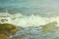 Sea surface with white wave over beach stones. Seashore under sun toned photo. Royalty Free Stock Photo