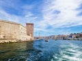 Sea surrounded by buildings and ships under a cloudy sky and sunlight in Marseille in France Royalty Free Stock Photo