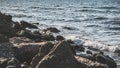 Sea tidal waves of the Black Sea break on a rocky shore and stones, forming splashes and foam of salt water Royalty Free Stock Photo