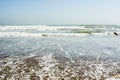 Sea tidal waves with white foam on a sunny sandy beach in resort Royalty Free Stock Photo