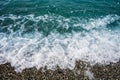 Sea tide on a pebble shore. Waves with white foam on a pebble beach. Nature concept, background