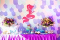 Sea time mermaid theme on the party`s candy bar with purple background. Birthday party for girls, teens