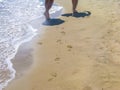 The sea transparent clear wave gradually washes away traces on the sand left by happy people Royalty Free Stock Photo