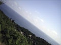 Sea view from the coastal mountains. The coastal hills are surrounded by dense vegetation, including low buildings. In the